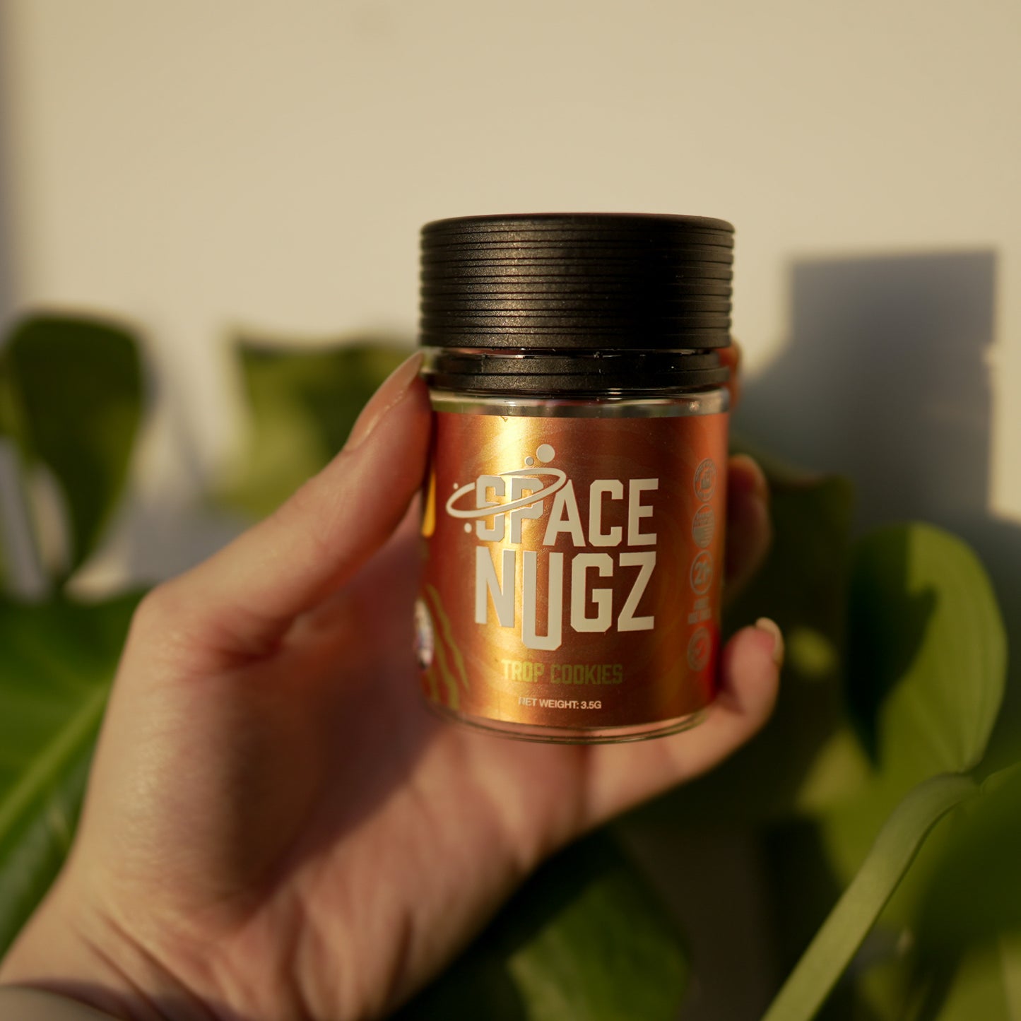 Trop Cookies THCA Flower - Sativa Flower Strain - Woman Holding Jar In Front of Plants - Galaxy Treats in the U.S.