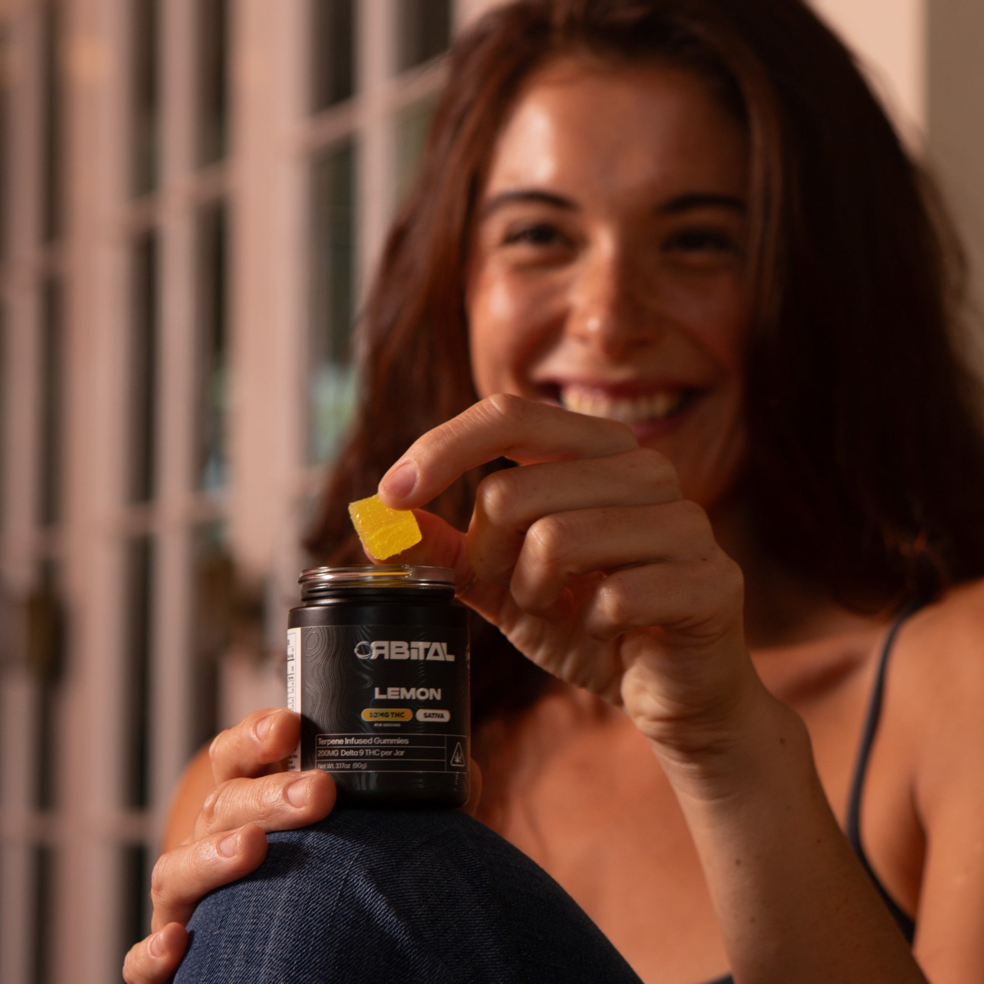Lemon Delta 9 Gummies - 10MG Delta 9 - Woman Picking Gummy from Jar Smiling - Galaxy Treats in the U.S.
