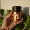 Trop Cookies THCA Flower - Sativa Flower Strain - Woman Holding Jar In Front of Plants - Galaxy Treats in the U.S.