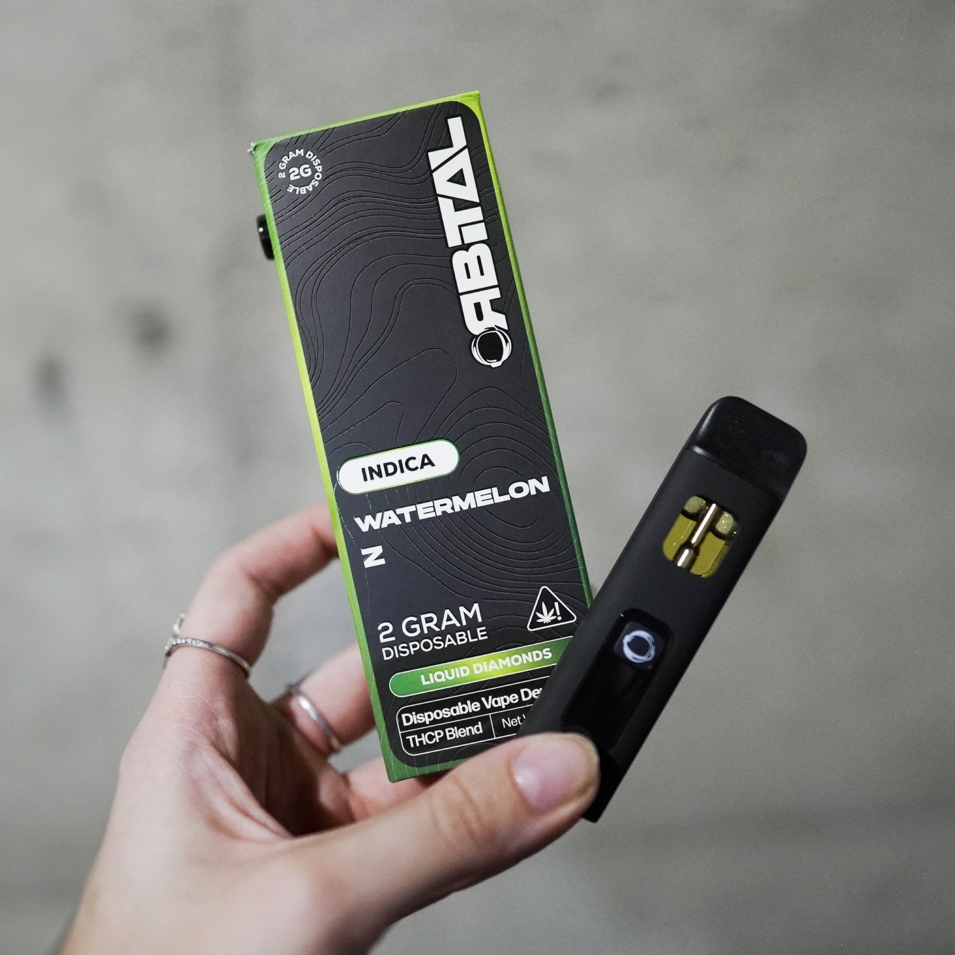 Watermelon Z Vape - Orbital 2G Sativa Disposable - THCP Liquid Diamonds - Hand Holding Packaging Box and Device - Galaxy Treats in the U.S.